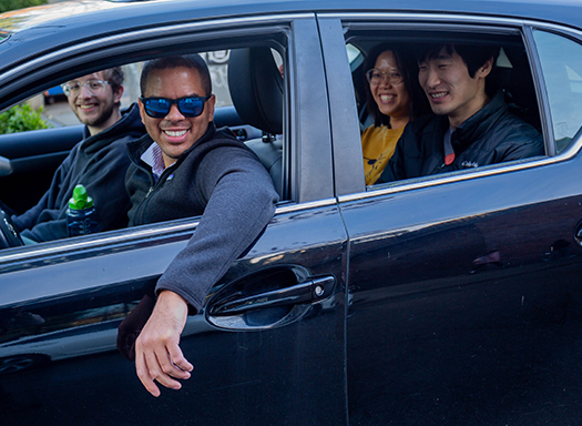 four students in a car very happily carpooling 