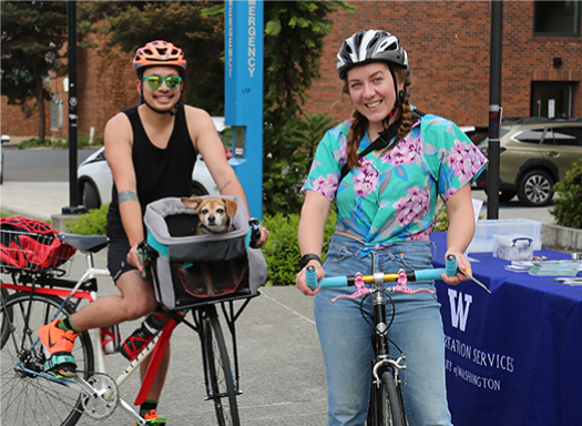 Two biking commuters smiling with their small dog inside a front bike basket