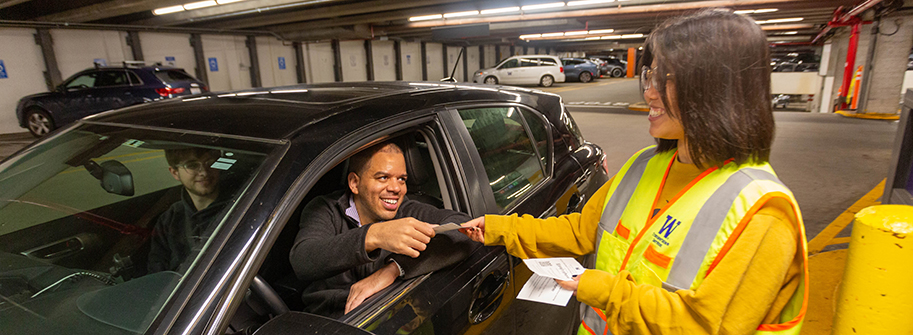 car driver receiving parking permit from a staff person at the central plaza garage gatehouse