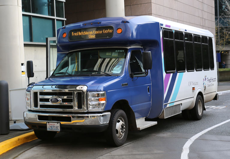 blue and white fred hutchinson cancer center clinic shuttle bus parked at curb