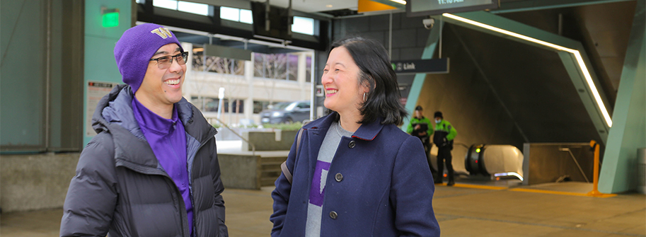 two staff members smiling and talking as they exit u district light rail station