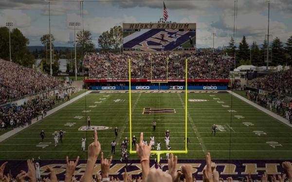 football game at husky stadium with fans raising their hands in the foreground