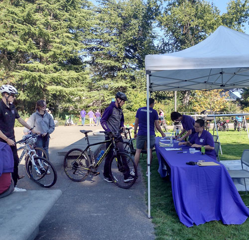 bike riders line up to valet their bikes on a sunny game day