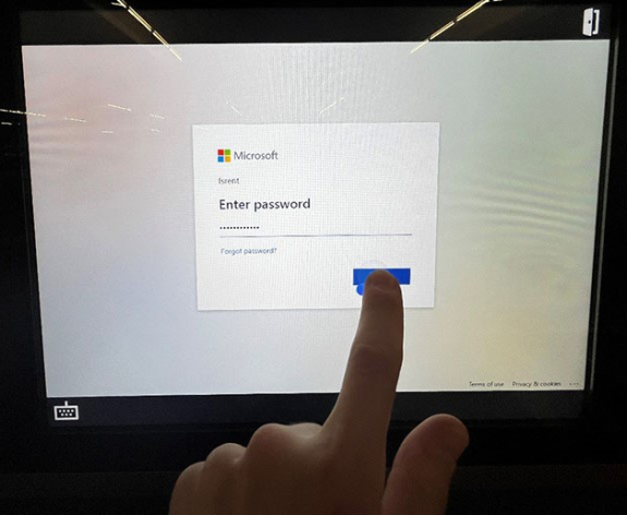 key manager kiosk screen showing password filled in at uw office 365 sign in screen and person's finger pressing sign in button