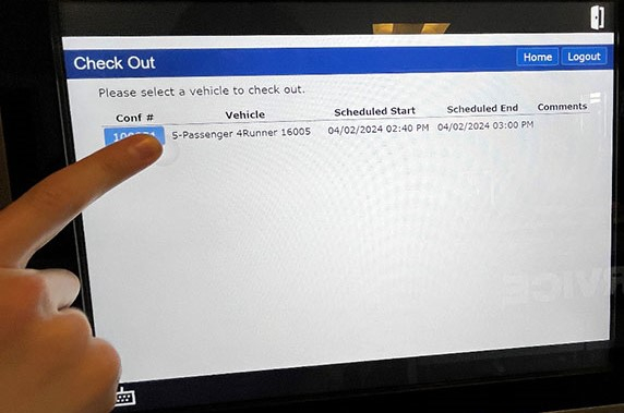key manager kiosk screen showing check out screen and vehicle listed with person's finger tapping confirmation number button