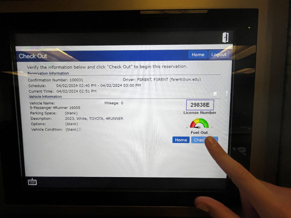 key manager kiosk screen showing vehicle reservation information and vehicle fuel detail with person's finger about to tap check out button