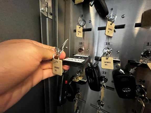 key manager box interior showing person's hand holding key and keycard partially removed from slot 15
