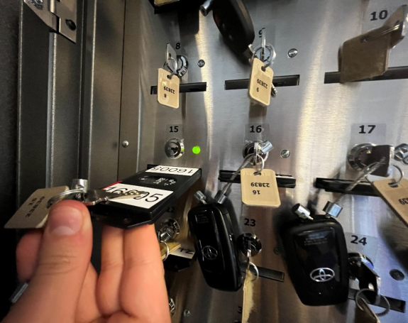 person's hand sliding key fob card into slot number 15 in key manager box