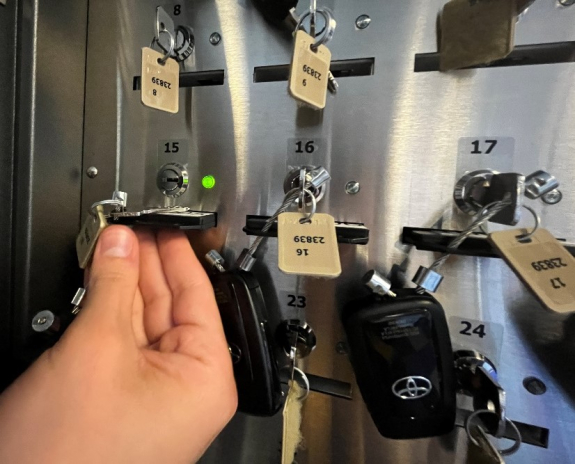 person's hand sliding key fob into slot in key manager box with key fob fully inserted