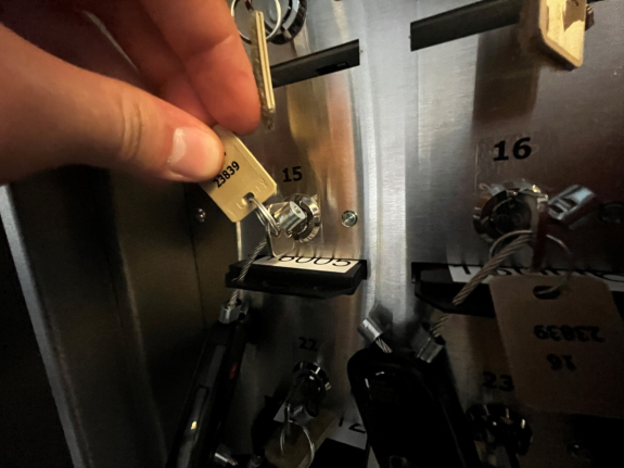 person's hand holding key fob tag with key fully inserted and rotated in key manager box at slot 15 with green light off