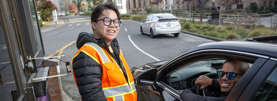 car driver receiving assistance from a staff person at a gatehouse