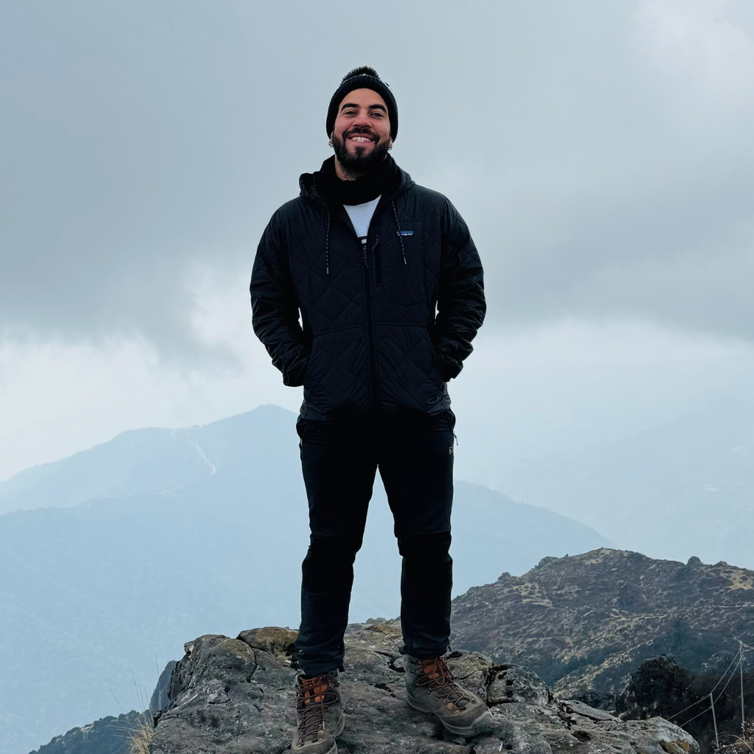 A photo of Hector standing on a mountain top, with a grey skey behind