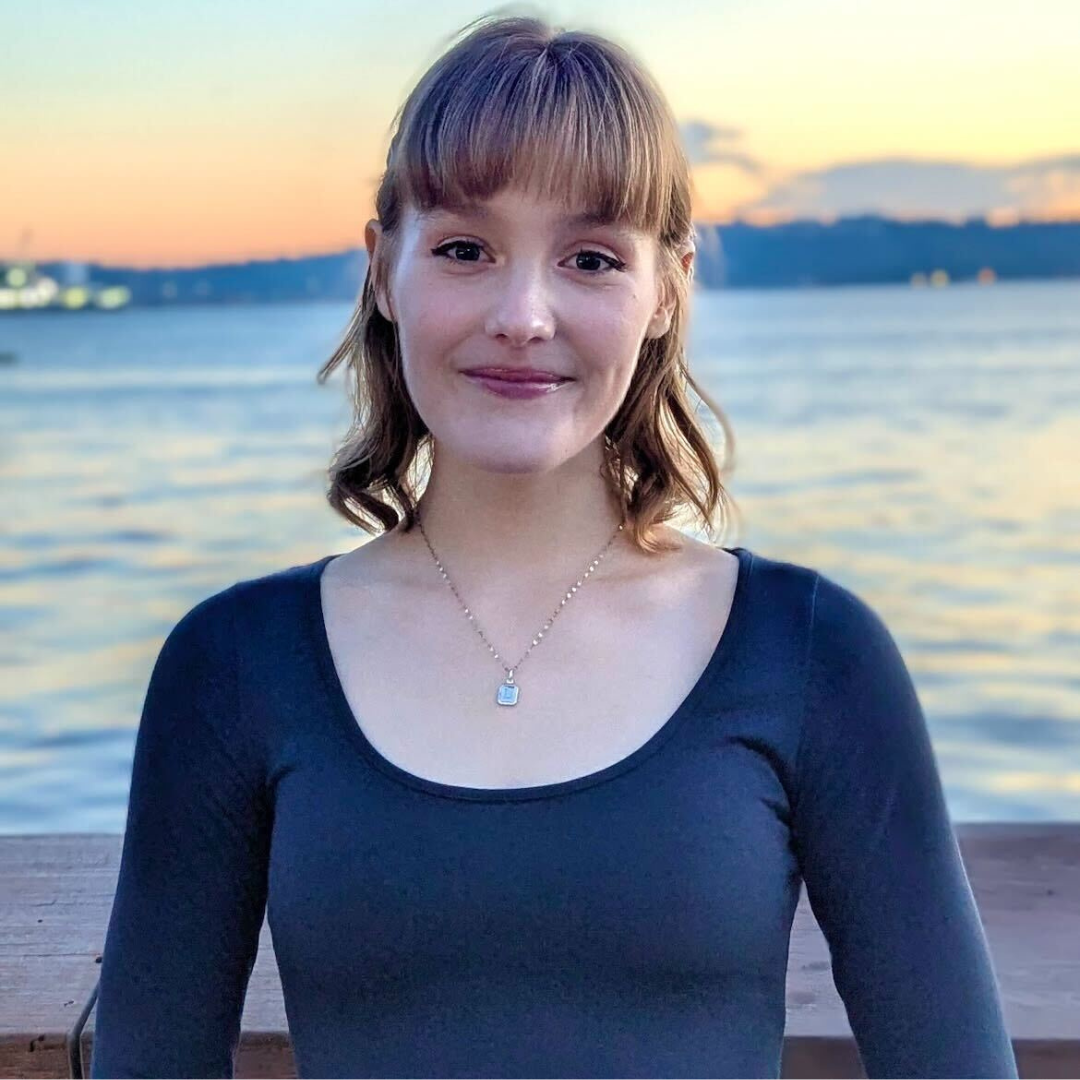 A photo of Laura outside in front of the water, at sunset.