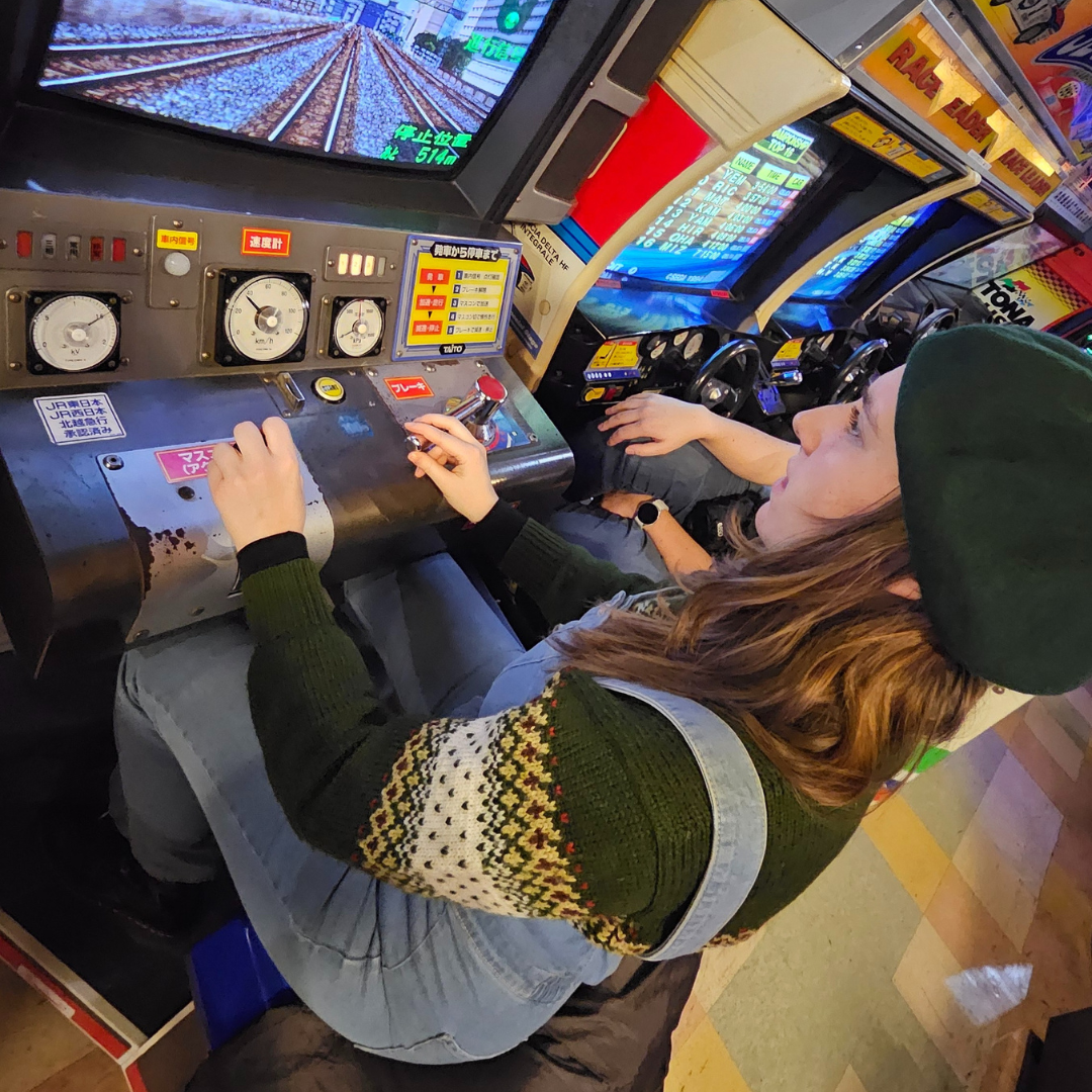 A photo of Zoe sitting at a retro arcade game