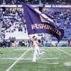 male student carrying flag across field at start of uw husky game